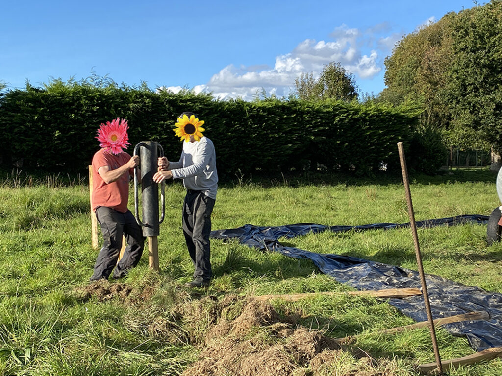A l'aide d'une cloche, les poteaux sont plantés.